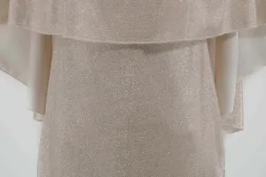 Nahaufnahme der funkelnden Champagner Abendkleid Stofftextur mit elegantem Rüschendesign.