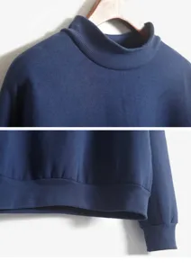 Detailopname van de donkerblauwe sweater met opstaande kraag en geribde boorden.