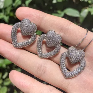 Gros plan detaille du scintillant ensemble de collier et boucles d'oreilles double coeur.