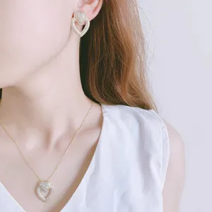 Vue détail de boucles d'oreilles et collier cœur en strass stylés, design minimaliste et élégant.