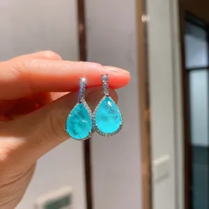 Detaillierte Nahaufnahme von birnenförmigen blauen Edelstein-Ohrringen mit funkelnden Zirkonen.