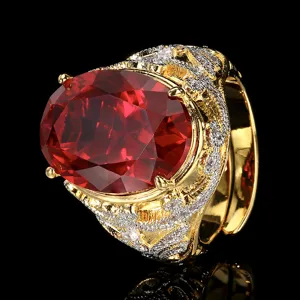 Close-up detail of vintage gold plated ring with large oval red gemstone and clear zircon stones.