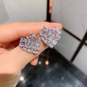 Detalle de pendientes de tuerca en forma de corazón con circonitas en tono plateado.