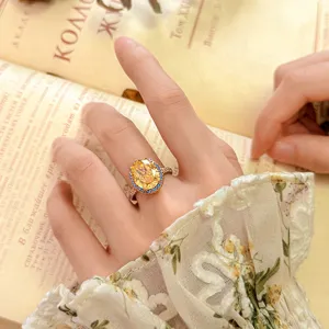Elegante anello vintage con gemma ovale gialla, alone di cristallo blu e fascia in oro rosa.