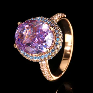 Primo piano dettagliato di un anello di cristallo rosa ovale di lusso con pietre blu e bianche.