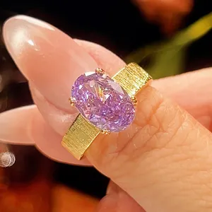 Detalle cercano de anillo de lujo de circonita púrpura con banda ancha cepillada chapada en oro.