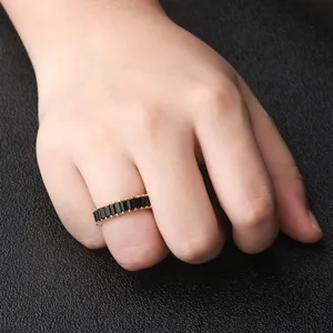 Elegant gold-tone ring featuring sparkling black baguette cubic zirconia stones on hand.