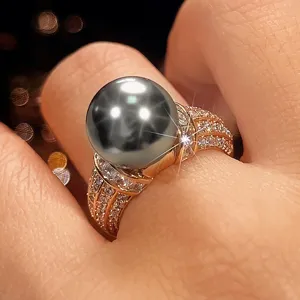 Primo piano di un anello vintage placcato in rame con perla scura e pietre lucide brillanti.