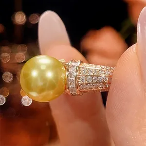 Primo piano dettagliato di anello perla dorata, fascia zirconi vintage, gioiello raffinato.