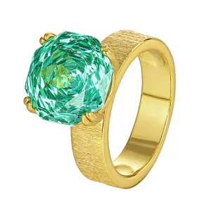 Primo piano dettagliato dell'anello texturizzato placcato in oro con grande pietra verde.