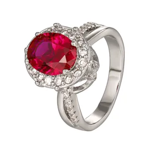 Vista detallada del elegante anillo de piedra roja ovalada con halo de circonitas brillantes.