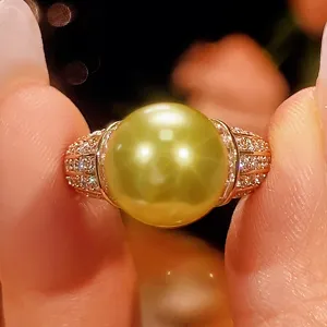 Primo piano dettagliato di un anello con perla dorata e zirconi scintillanti in stile vintage.