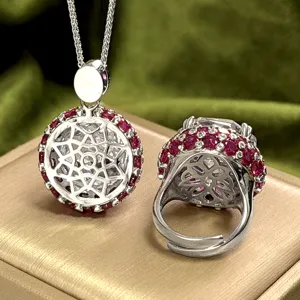 Gros plan détaillé de l'ensemble pendentif et bague argentés avec des accents rouges vibrants.
