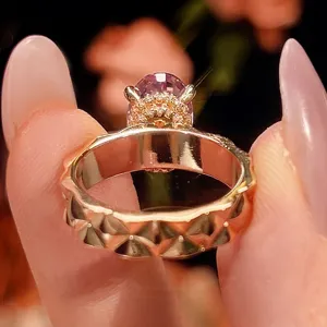 Dettaglio in primo piano dell'anello in oro rosa con gemma sfaccettata e fascia geometrica.