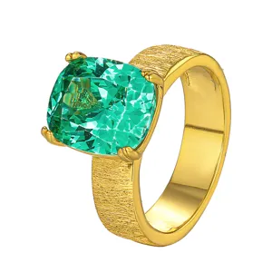 Gros plan de la bague en pierre précieuse verte taillée en coussin et or brossé.