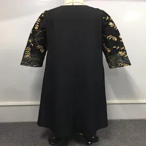 Vista dettagliata dell'abito nero con maniche in rete trasparente e ricamo floreale dorato.