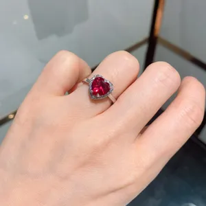 Detailaufnahme des atemberaubenden herzförmigen roten Edelsteinrings am Finger getragen.