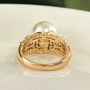 Primo piano dettagliato dell'anello in rame dorato con lavorazione traforata e perla.