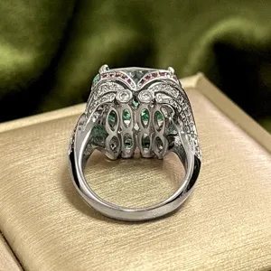 Vintage silver-tone emerald-cut green gemstone ring with paved stones and intricate hollow gallery.