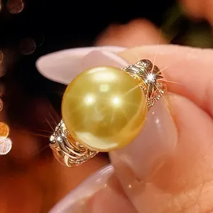Dettaglio in primo piano dell'anello di perle dorate 12mm con fascia metallica decorata.
