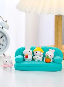 Deliziose mini figurine di coniglio su divano ciano, primo piano dettagliato per interni.