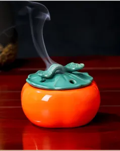 Detalle de quemador de incienso de cerámica, forma de caqui con tapa de hoja verde.