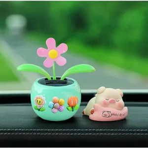 Close-up detail of cute solar shaking flower pot and sleeping pig car dashboard ornament.