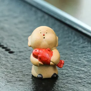 Petite figurine de moine en céramique tenant un poisson rouge animal de thé déco