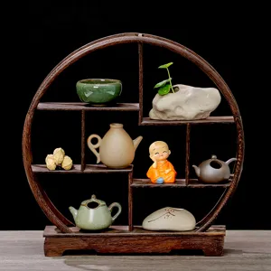Étagère ronde en bois massif avec mini théières et figurine de moine pour décoration de table à thé.