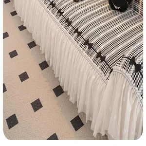 Detailed view of chenille sofa cover featuring black grid pattern and white mesh lace skirt.