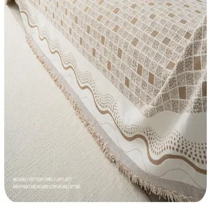 Detailed view of the soft knitted sofa cover with geometric pattern and elegant fringe trim.