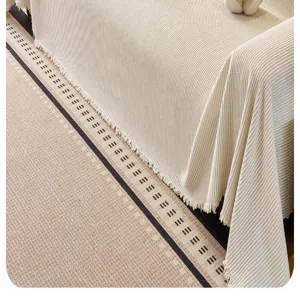Detailed view of beige striped chenille sofa cover, soft knitted blanket with fringe.