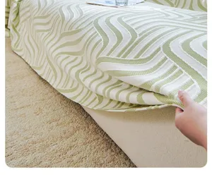 Close-up detail shot of the cooling silk sofa cover featuring a chic textured green wave pattern.