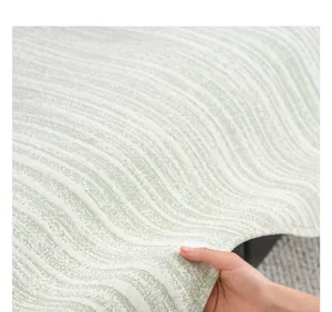 Close-up detail of ice silk sofa cover fabric, soft cooling material texture in green.