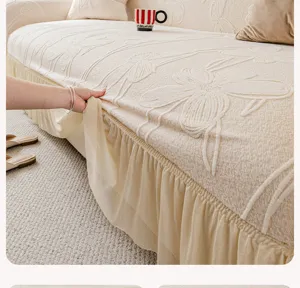 Close-up detail of beige jacquard sofa cover with elegant pleated skirt and floral pattern.