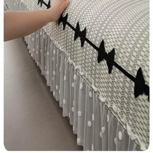 Detail view of houndstooth sofa cushion cover with black bows and white dot mesh ruffles.