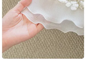 Close-up detail of white pleated ice silk sofa cushion fabric with delicate lace edge trim.