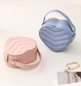 Detailed view of portable heart-shaped leather jewelry boxes in pink and blue for travel.