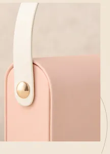 Close-up of portable jewelry box showing pink leather, white handle and gold hardware.