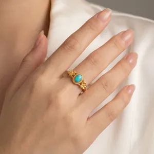 Close-up view of an elegant gold-plated floral ring featuring a vivid oval turquoise stone.