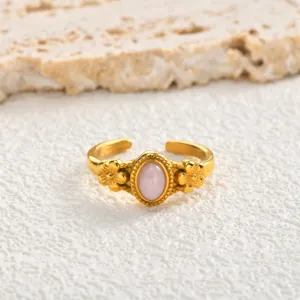 Close-up detail of gold stainless steel open ring with oval pink stone and cute flowers.