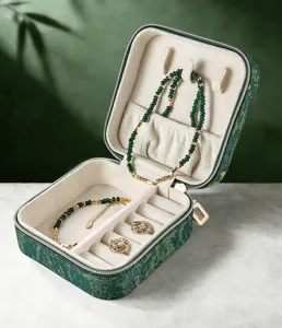 Detailed view of portable green jewelry box with velvet lining, storing delicate necklaces.