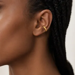 Nahaufnahme eines minimalistischen goldenen Ohrklemmergehängs am Knorpel, schicker Schmuck.