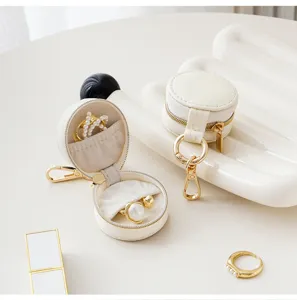 Portable mini round jewelry box detail showing ring storage, compact keychain zipper pouch.
