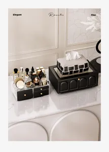 Detail view of a luxury black and clear makeup organizer and leather tissue box on a marble top.