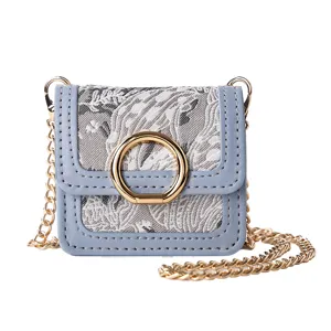 Mini blue jacquard crossbody bag with gold chain strap and metal ring clasp detail.