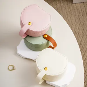 Portable round travel jewelry box organizer with handle and snap button for rings and earrings.