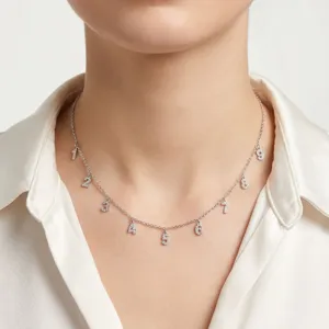 Detalle de un collar de cadena plateada con dijes numéricos de circonita brillante 1-9.