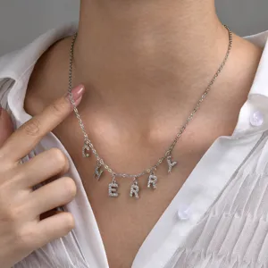 Primer plano de un collar personalizado de acero inoxidable plateado con dijes de letras.