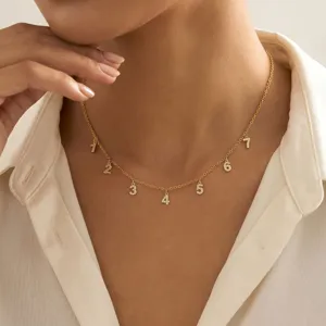 Detalle de primer plano de collar de cadena dorada con dijes numéricos de circón.